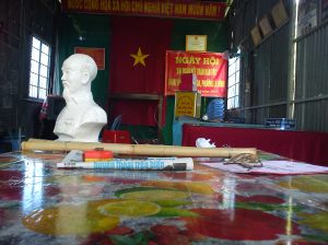 A bust of Ho Chi Minh, the Vietnamese flag and the stick of a local officer placed on his desk in an urban commune of the Mekong Delta. Source: the author, 2011. 